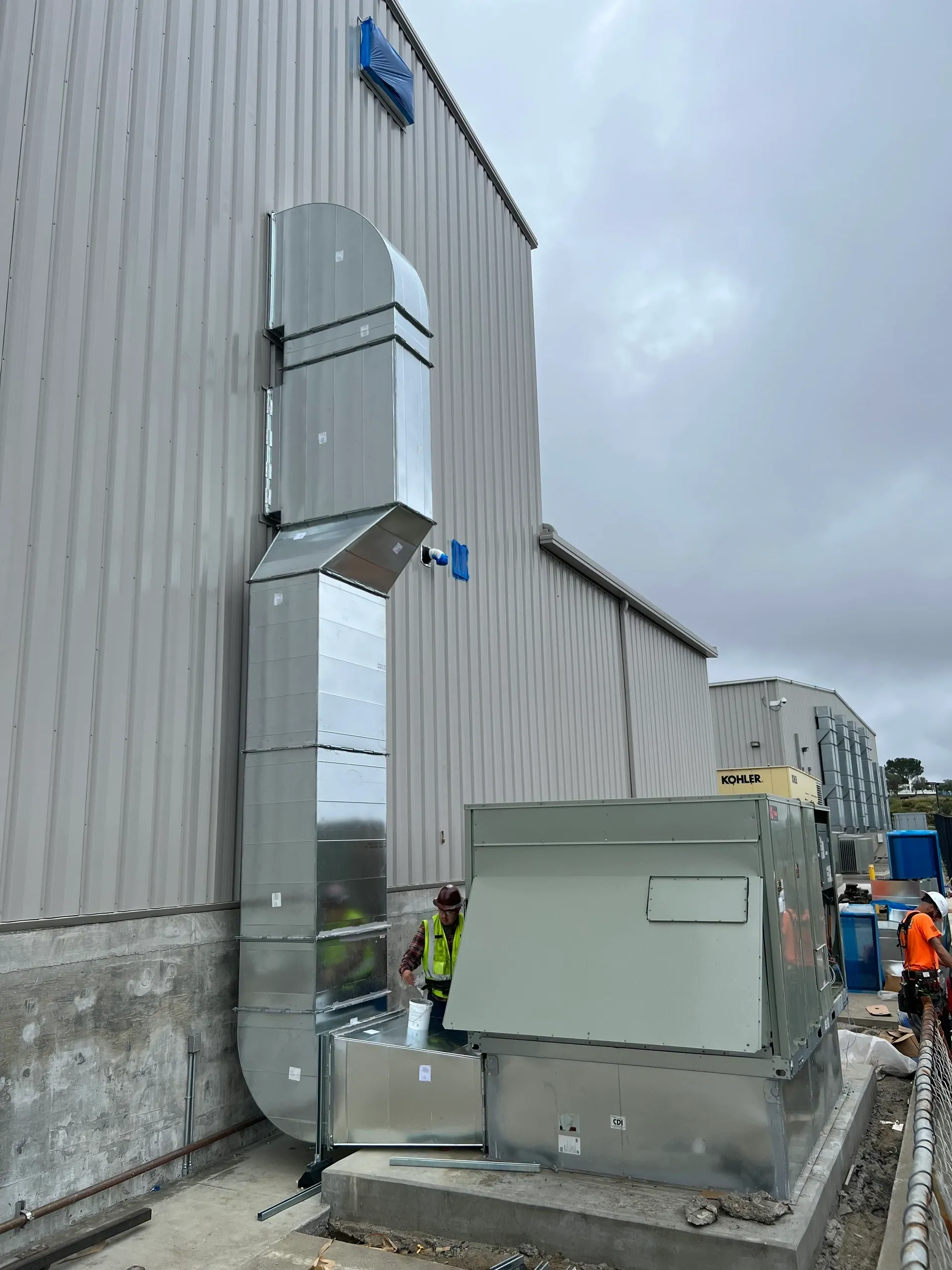 Large outdoor HVAC units and ductwork are installed beside a building.