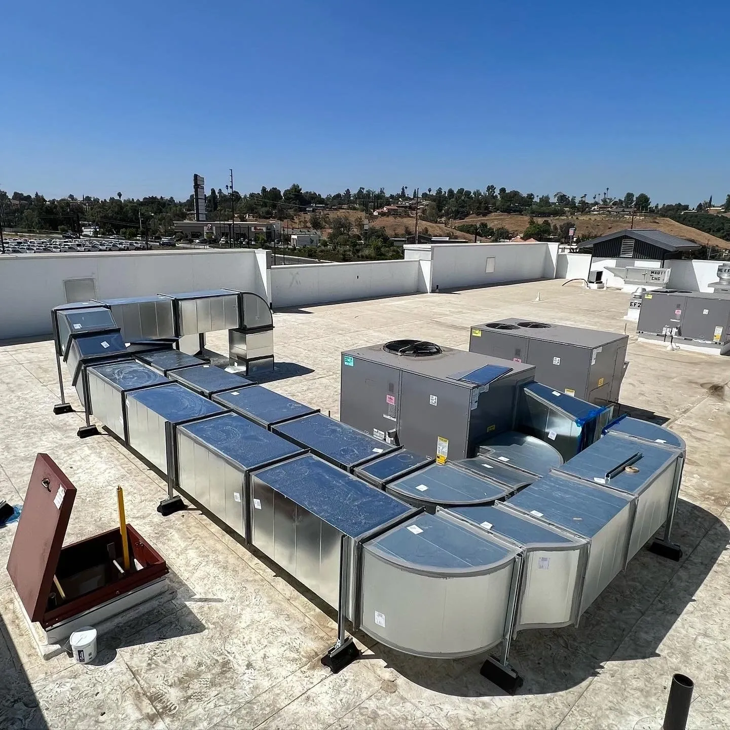 Extensive rooftop HVAC units and silver ductwork are seen on a building.