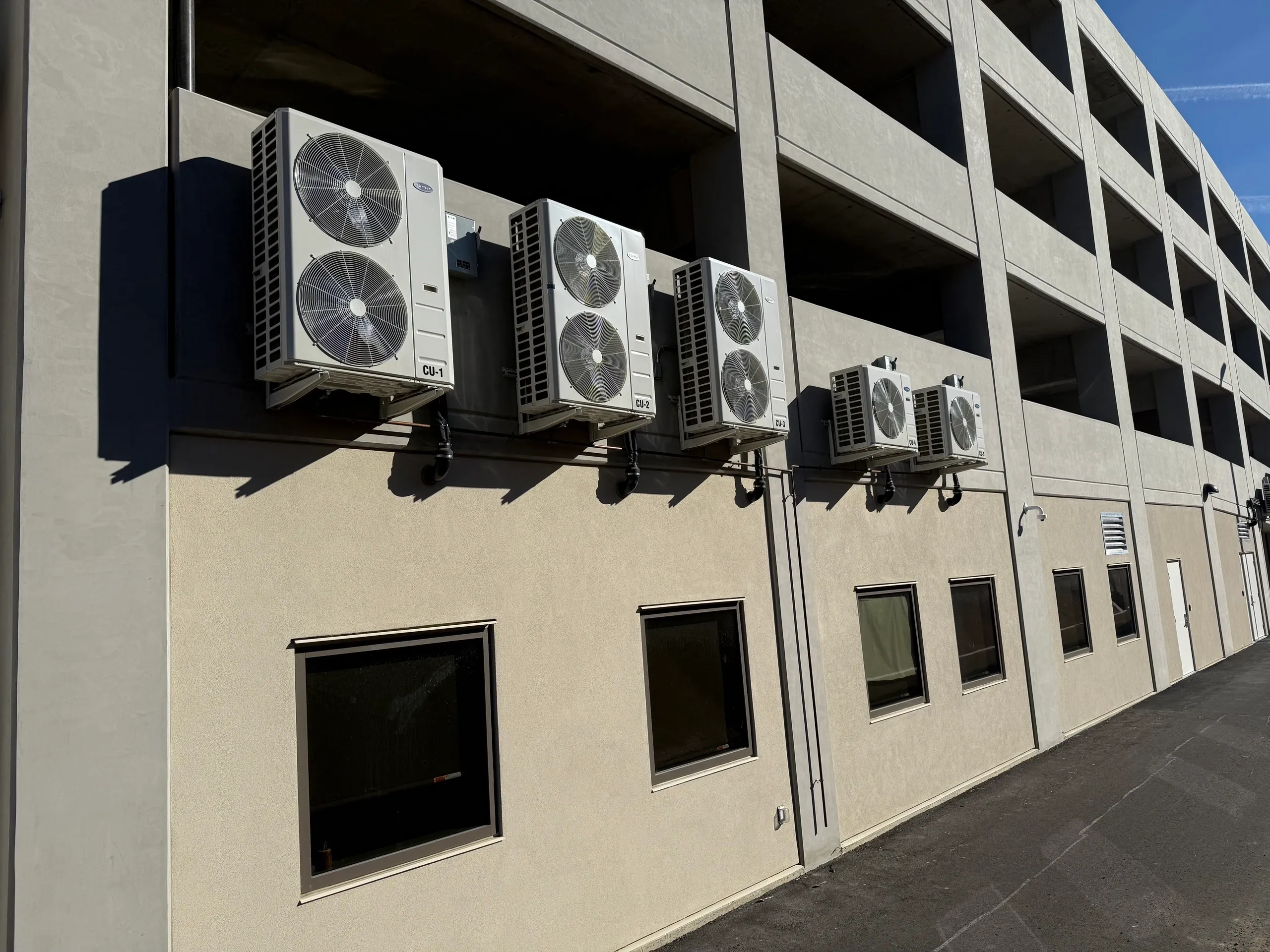 Multiple outdoor AC units are mounted on the side of a commercial building.